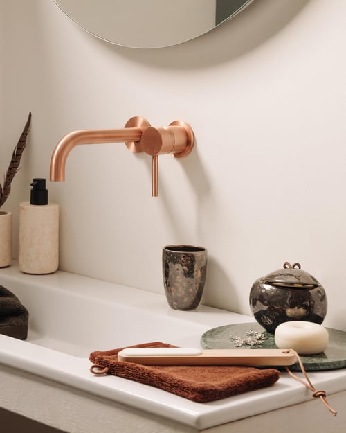 Witte badkamer met roos gouden kraan en houders van bruin en beige keramiek