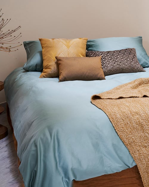 Boutique hotel slaapkamer met licht blauw beddengoed van Essenza sierkussens en een donkergele sprei